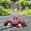 Berries & White Chocolate Wax Melt pouch surrounded by fresh berries and white chocolate pieces